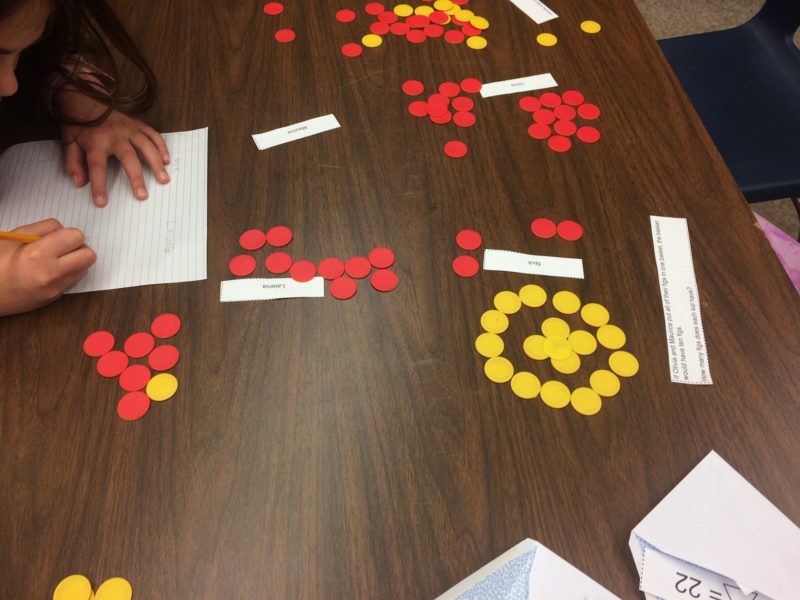 Children using counters to keep track of quantities while working through a word problem.